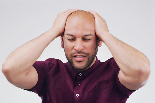 bald man with painful scalp two hands on head