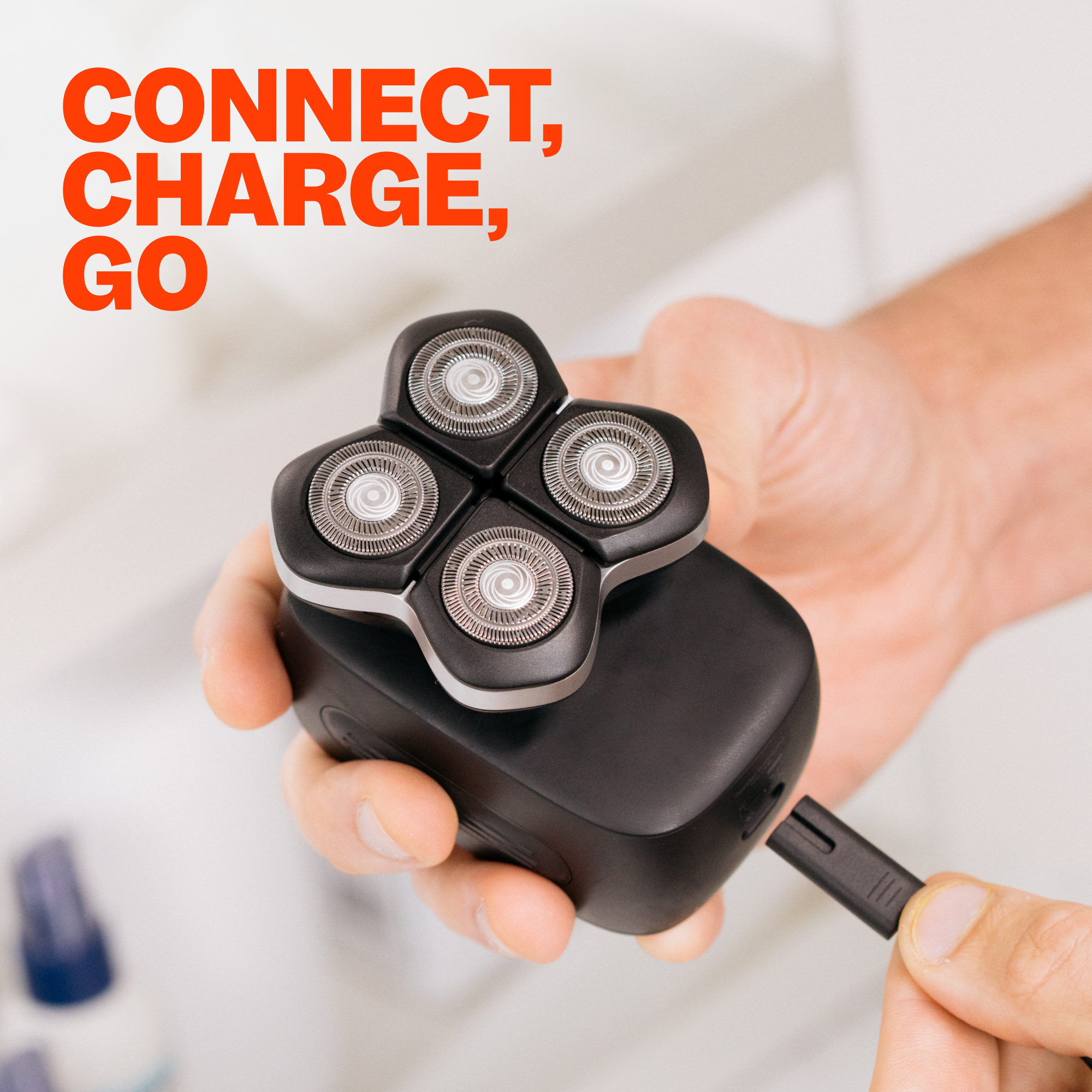 Hand holding a black electric shaver equipped with four rotary blades and the FlexSeries® Pro USB Charging Cable by Freebird. Text: Connect, Charge, Go. Remember to fill out all product specs for the ultimate shaving experience!