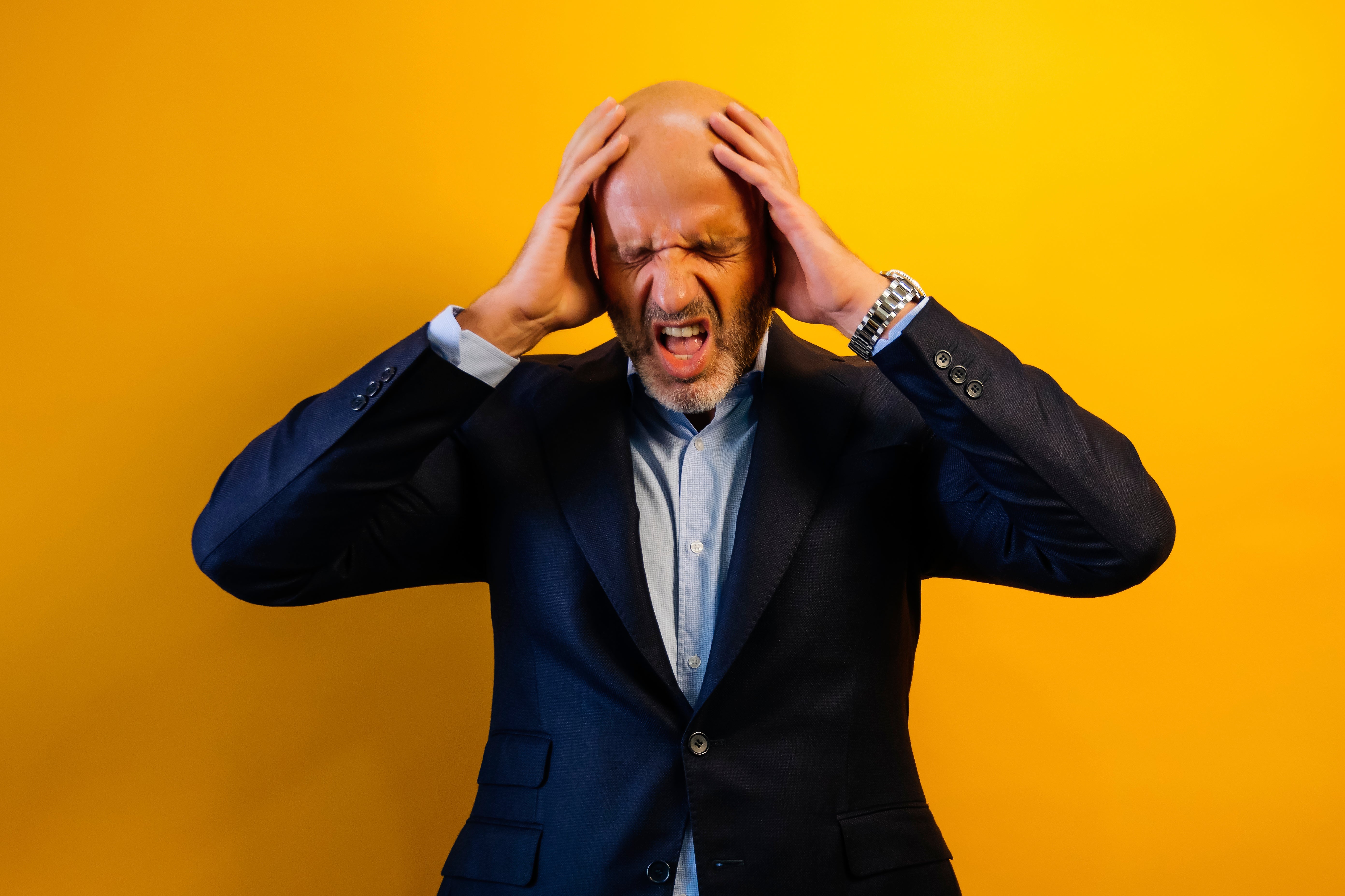 bald man frustrated with both hands on head