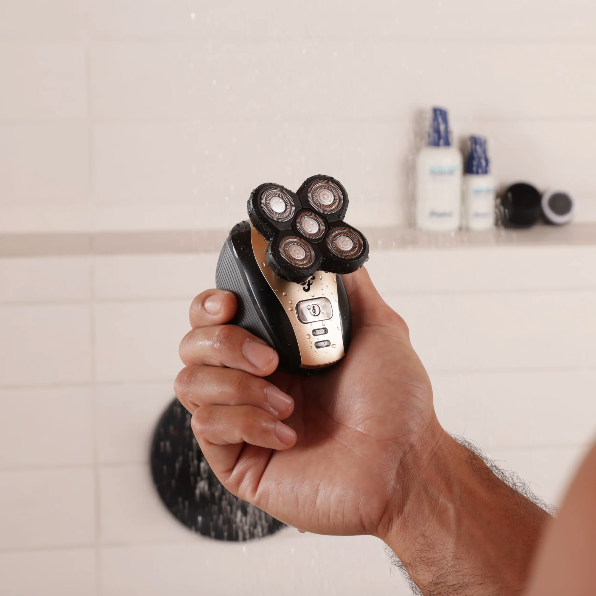 A hand holding the FlexSeries® Shaving Kit by Freebird, equipped with ScalpSafe™ Technology, in a shower surrounded by shampoo bottles, ensures a smooth shave for every skin or hair type.