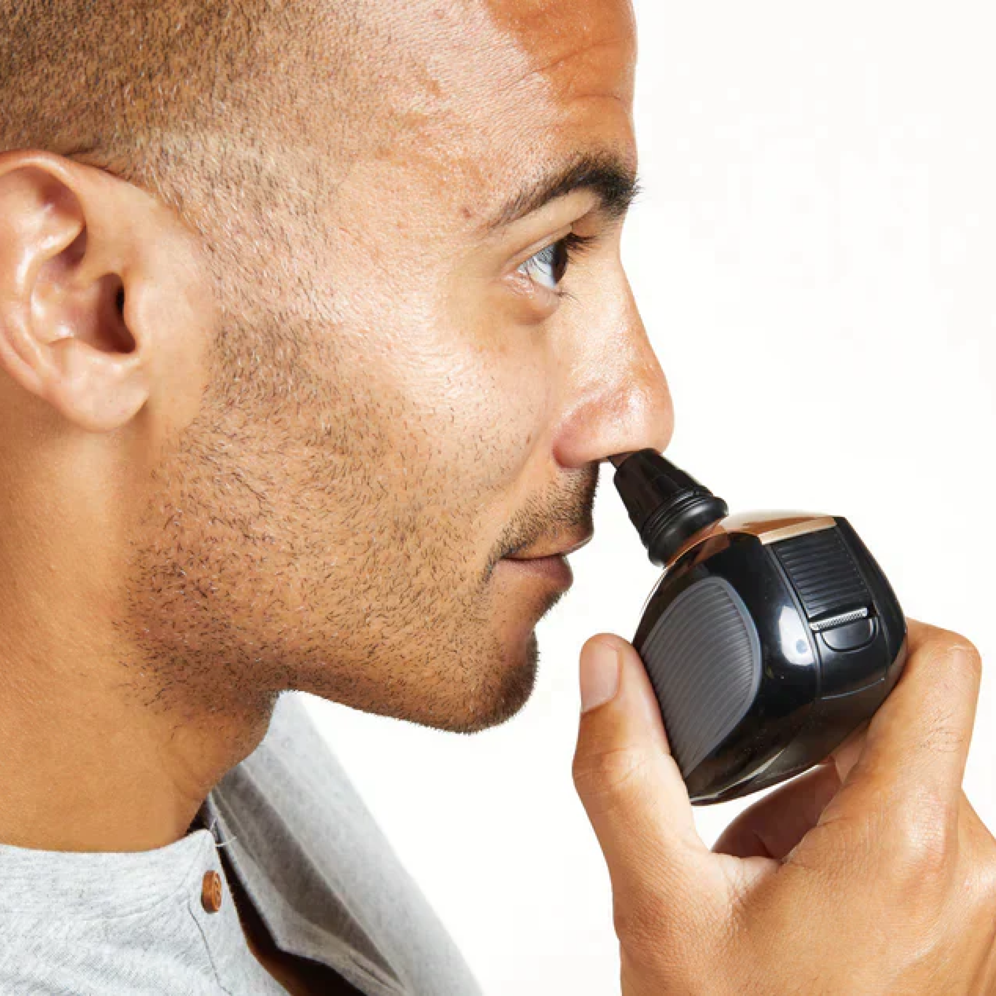 A man expertly uses a trimmer from the FlexSeries® Shaving Kit by Freebird, featuring ScalpSafe™ Technology for a precise and worry-free trim on his nostril.