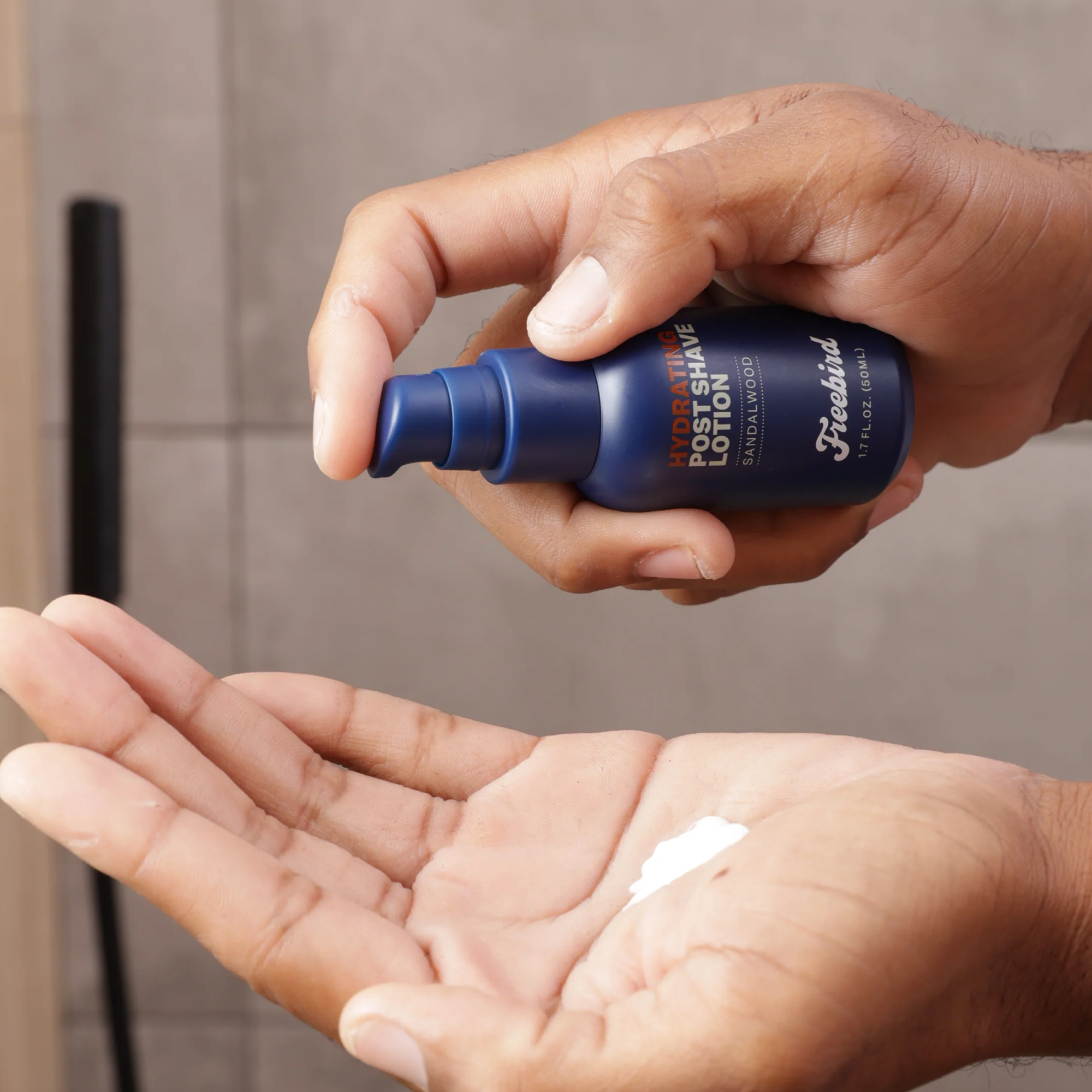A person applies Freebirds Hydrating Post-Shave Lotion from a blue bottle to their hand, reducing dryness for smoother skin.