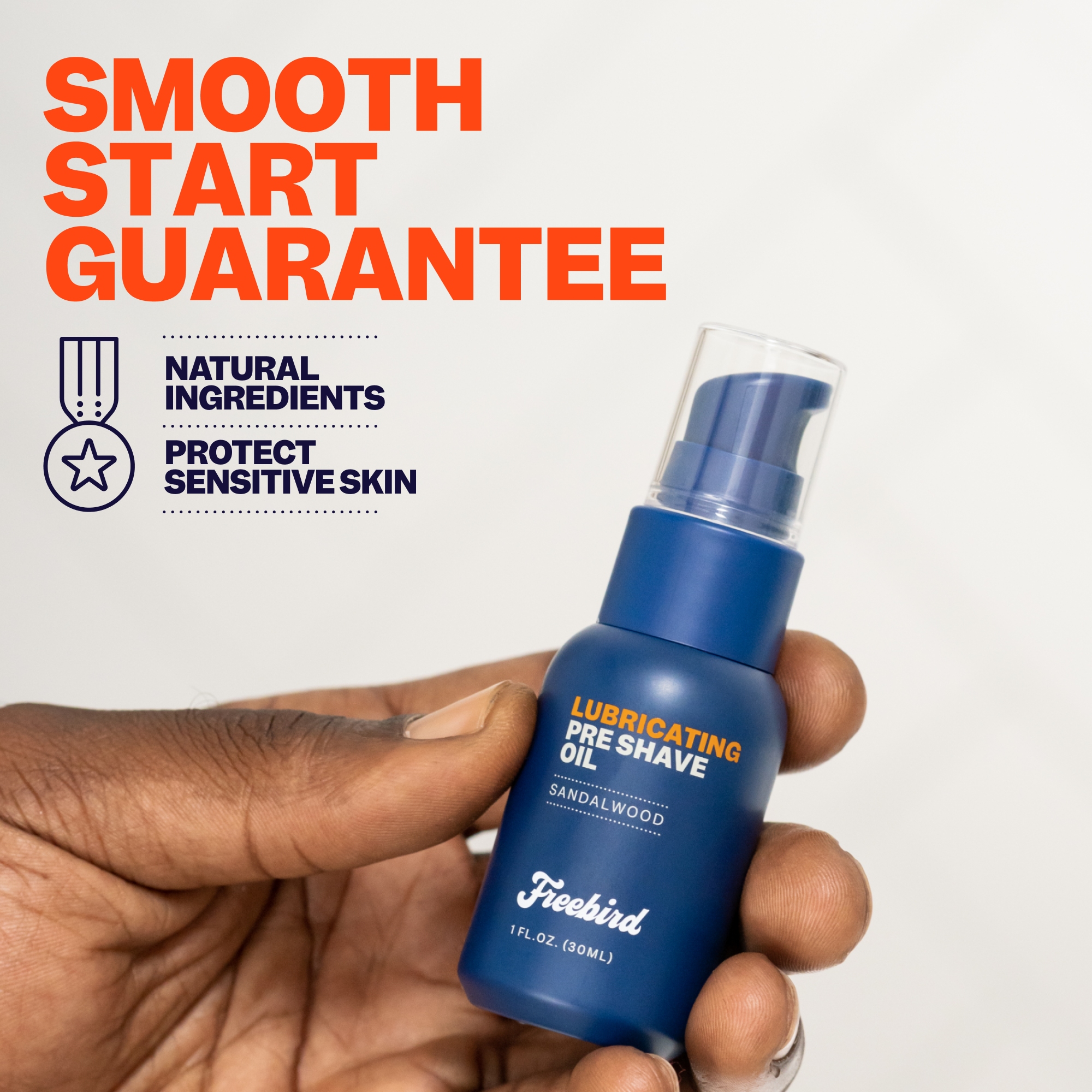 A hand holds a blue bottle of Freebird's Lubricating Pre Shave Oil against a white background, emphasizing its natural ingredients and the nourishing benefits of grapeseed oil for enhanced skin protection.